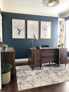 a home office with blue walls and wooden furniture in the corner, along with two framed pictures on the wall