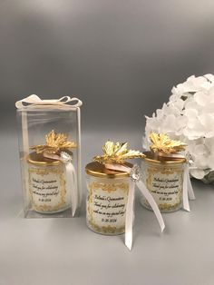 three glass jars with gold decorations and ribbons on the top one has a ribbon tied around it