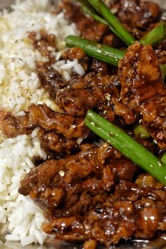 a close up of rice and meat on a plate with green beans in the foreground