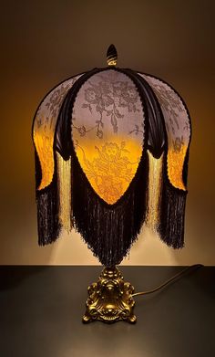 a lamp with an intricately designed shade on it's base and tassels