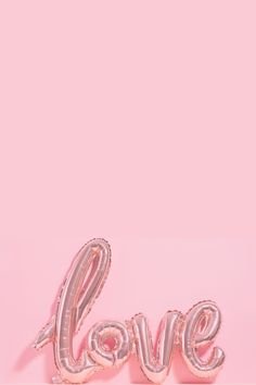 the word love is made out of foil balloons on a pink background with a heart shaped balloon