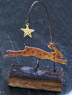 a small metal deer on top of a piece of wood with a star hanging from it's back