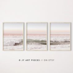 three framed art pieces on a white wall with the ocean in the background and text above them