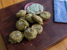 a wooden cutting board topped with cookies next to a small bowl of dipping sauce on top of it