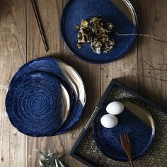 two plates with food on them sitting on a wooden table next to utensils