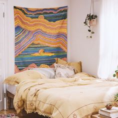 a bed sitting in a bedroom next to a wall hanging on the side of a wall