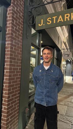 a man standing in front of a j stark store with his hands in his pockets