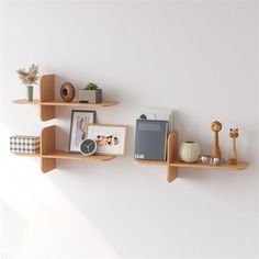 three wooden shelves on the wall with pictures and other items in them, one is empty