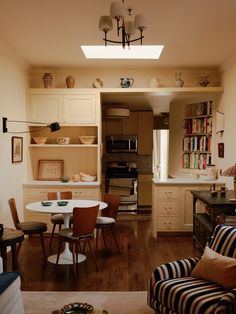 a living room filled with furniture next to a kitchen and dining room table in front of a stove top oven