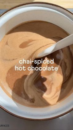 a bowl filled with hot chocolate sitting on top of a table next to a spoon