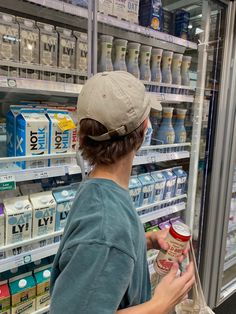 a woman in a hat is looking at milk and yogurt on the shelf