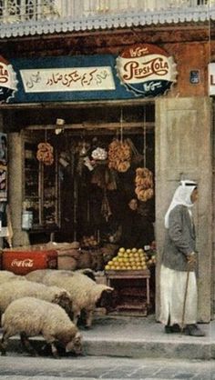 a man standing in front of a store with sheep