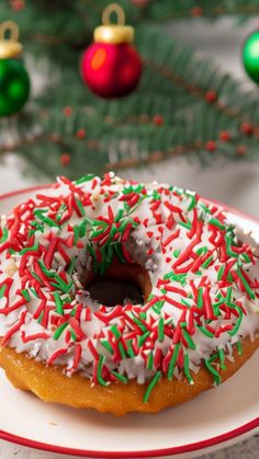 a frosted donut with sprinkles on a plate next to christmas decorations