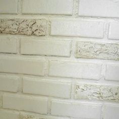 a white toilet sitting in front of a white brick wall with peeling paint on it