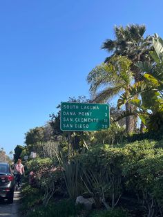 a street sign on the side of a road with trees and bushes in the background