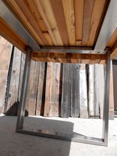 an empty wooden table with metal frame and wood slats on the wall behind it