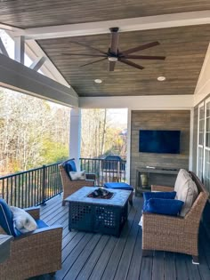 an outdoor living area with wicker furniture and ceiling fan on the deck overlooking trees