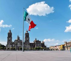 the mexican flag is flying in front of an old building with tall towers and arches