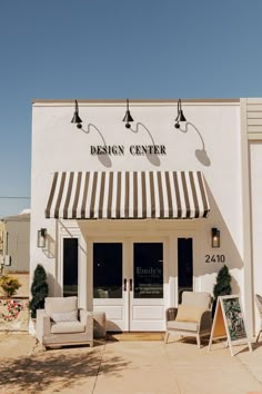 a white building with awnings and chairs outside