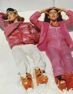 two women in pink snowsuits laying on the snow