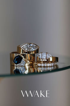 three wedding rings sitting on top of a glass table with the words wake written below them