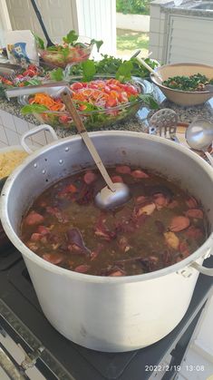 a pot filled with soup sitting on top of a stove next to other dishes and utensils