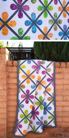 two quilts hanging on the side of a brick wall next to each other, one with