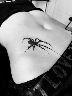 a black and white photo of a woman with a spider tattoo on her stomach