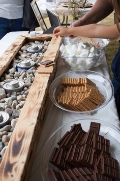 people standing around a table with food and drinks on it, including marshmallows