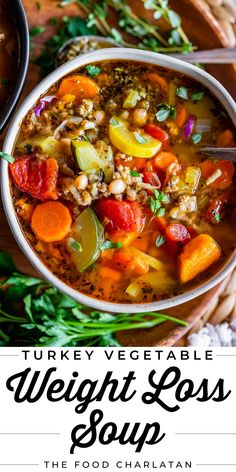 a bowl filled with turkey vegetable soup on top of a wooden table next to vegetables