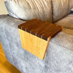 a wooden table sitting on top of a gray couch next to a grey sofa cushion