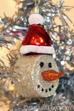 a snowman ornament on a christmas tree with silver tinsel and red hat