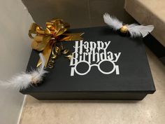 a black box with a happy birthday sign and some white feathers on the top that says harry potter