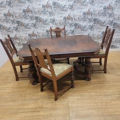 a wooden table with chairs around it on top of a hard wood floor next to a wall