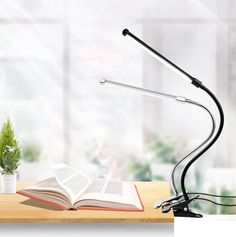 an open book sitting on top of a wooden table next to a lamp and potted plant