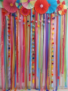 colorful streamers and paper umbrellas are hanging from the ceiling in front of a wall