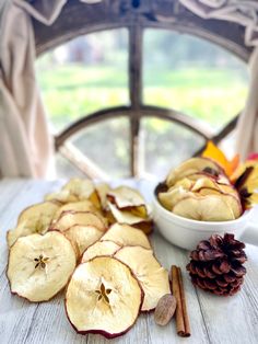 apples and cinnamon sticks on a table with a window in the backgroung