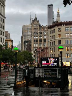 people are walking in the rain on a city street with tall buildings and green lights