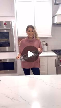 a woman standing in front of a kitchen counter with an oven and microwave behind her