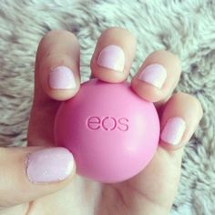 a woman's hand holding a pink ball with the word eos written on it