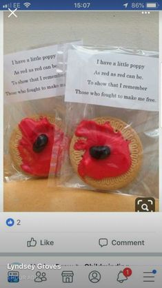 two cookies with red frosting and black centers in plastic wrap on top of a table