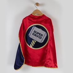 a red cape with the words super david printed on it and a hammer stuck into it