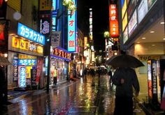 a person with an umbrella is walking down the street in the rain at night time