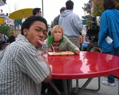 a man and woman sitting at a red table