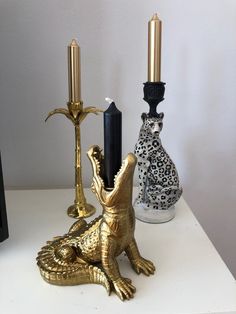 three different types of candle holders sitting on a table next to each other, one gold and the other black