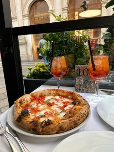 a pizza sitting on top of a white plate next to two glasses of orange juice