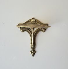 an ornate gold wall mounted shelf against a white wall