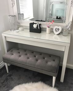 a white dressing table with a bench and mirror in the corner on top of it