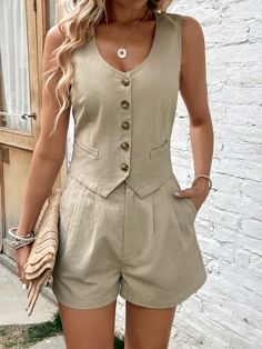 a woman standing in front of a white brick wall wearing a tan romper and shorts