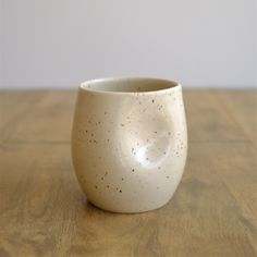 a white cup sitting on top of a wooden table